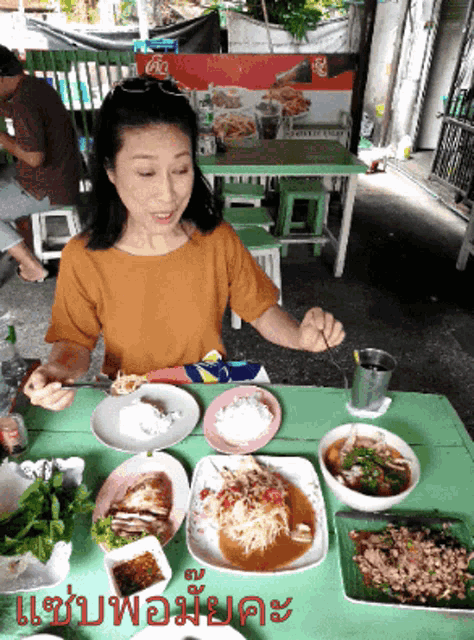 a woman is sitting at a table with plates of food and a sign that says coca cola