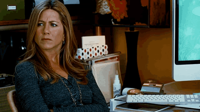 a woman sitting in front of a computer with a box labeled ' binders '
