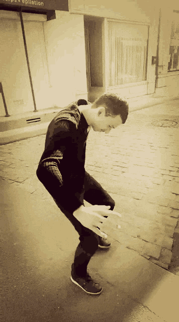 a man is squatting down in front of a building that says epilation on it
