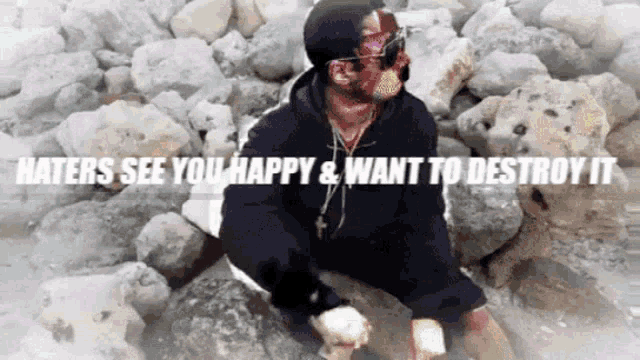 a man sitting on a pile of rocks with the words haters see you happy and want to destroy it above him