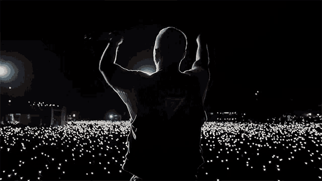 a man stands in front of a crowd with his arms in the air and a triangle on his back