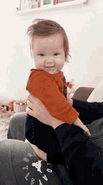 a person is holding a baby in their arms while sitting on a couch .