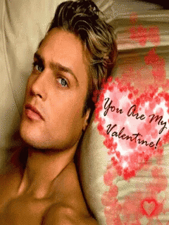 a shirtless man is laying on a bed with a valentine 's day greeting