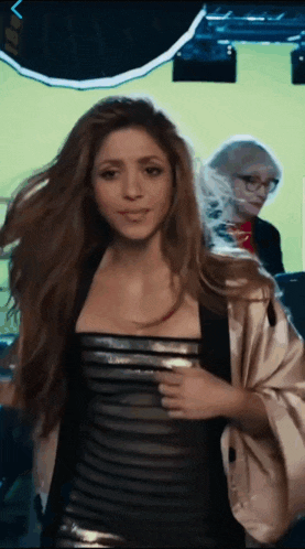 a woman in a black and silver dress stands in front of a green screen