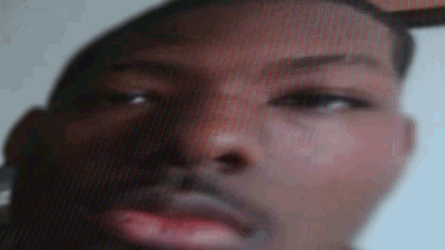 a close up of a man 's face with a blurred background and a red lip .