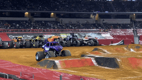 monster trucks are racing on a dirt track with a great clips sign in the background
