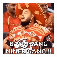 a man wearing a red sombrero and a red shirt is sitting in a crowd of people .