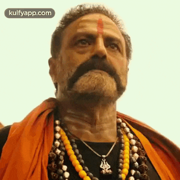 a man with a beard and a mustache is wearing a necklace and an orange scarf .