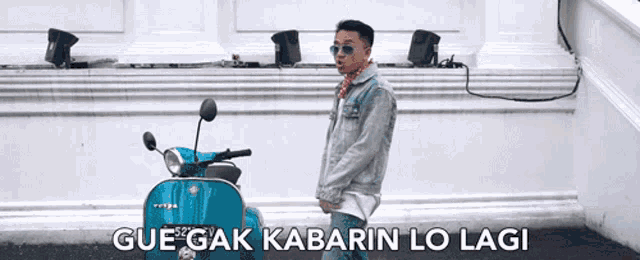 a man standing next to a vespa scooter with the words gue-gak kabarin lo lagi above him