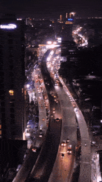 an aerial view of a highway at night with a building that says samsung in the background