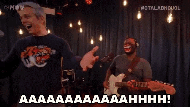a man singing into a microphone while another man plays guitar
