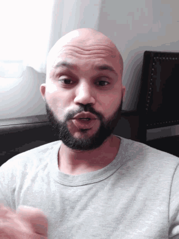 a man with a beard and a bald head looks at the camera