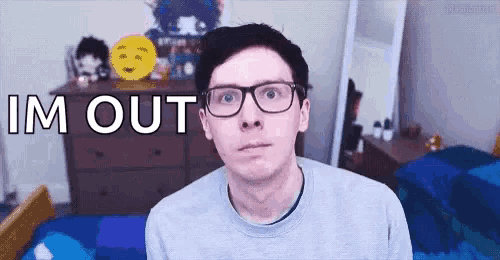 a young man wearing glasses and a sweater is standing in a bedroom with the words im out written on his face .
