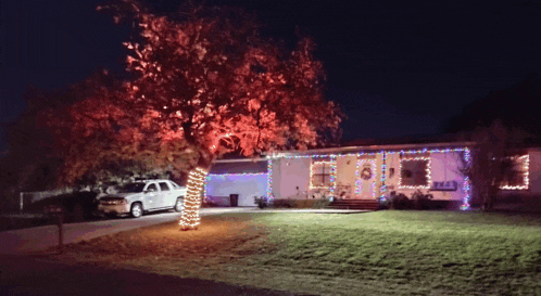 a white truck is parked in front of a house that has christmas lights on it