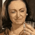 a woman is holding a glass of water and making a funny face .