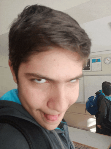 a boy making a funny face with his tongue out in front of a clock
