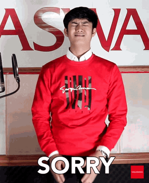 a man wearing a red sweater with the word sorry on it