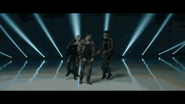 a group of people are dancing on a stage with a lot of lights behind them