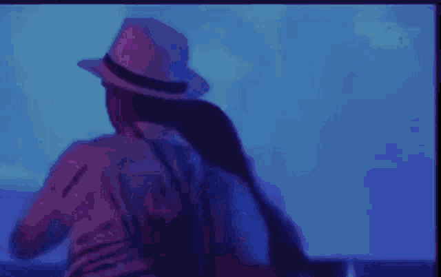 a man in a hat is standing next to a woman in a pink shirt .