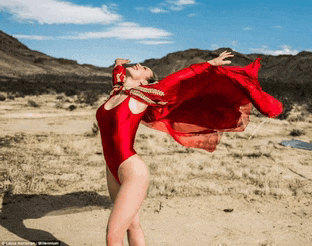 a woman in a red swimsuit is standing in the desert
