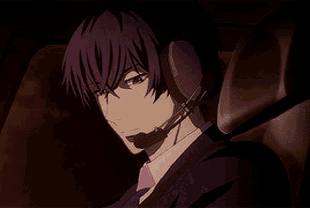 a man in a suit and tie is wearing a headset while sitting in a car seat .