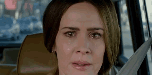 a woman with tears running down her face is sitting in a car