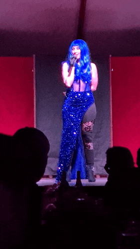 a woman with blue hair is singing into a microphone on stage