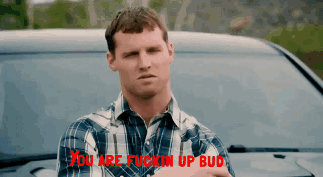 a man in a plaid shirt stands in front of a car with the words " you are fuckin up bud " on the bottom