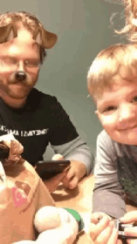 a man wearing a dog mask is holding a cell phone next to two young boys