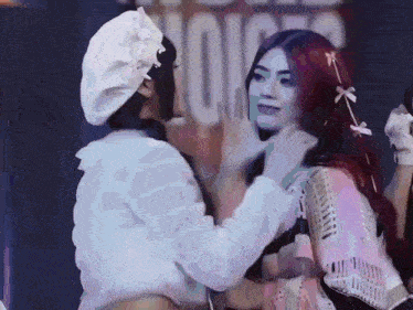 two women are touching each other 's faces in front of a microphone .