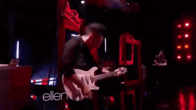 a man is playing a guitar on a stage with the words ellen behind him