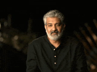 a man with a beard stands in front of a wow graphic