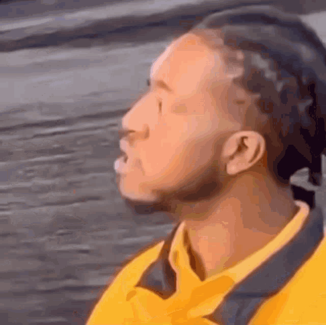 a man with dreadlocks and a yellow shirt is looking up .