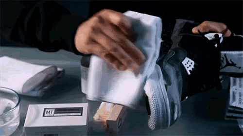 a person is cleaning a shoe with a cloth and a box that says mt on it