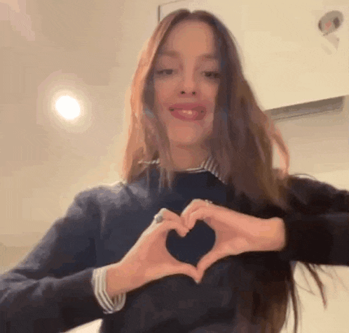 the girl is making a heart shape with her hands .