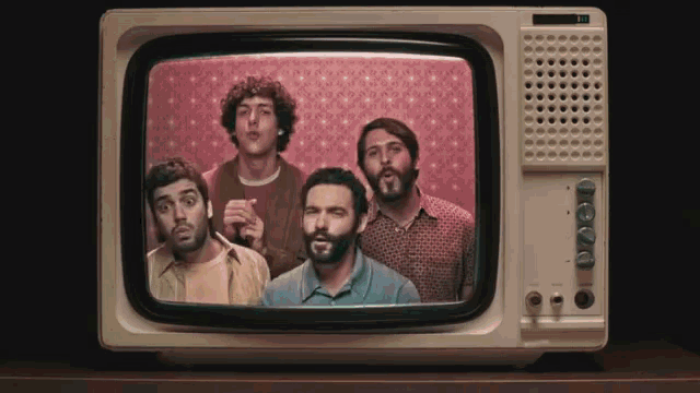 a group of men are standing in front of an old fashioned television with a pink background