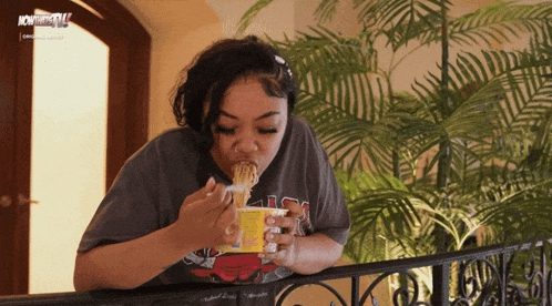 a woman eating noodles from a container that says now thatstv