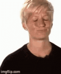 a woman with short blonde hair is wearing a black shirt and making a funny face .