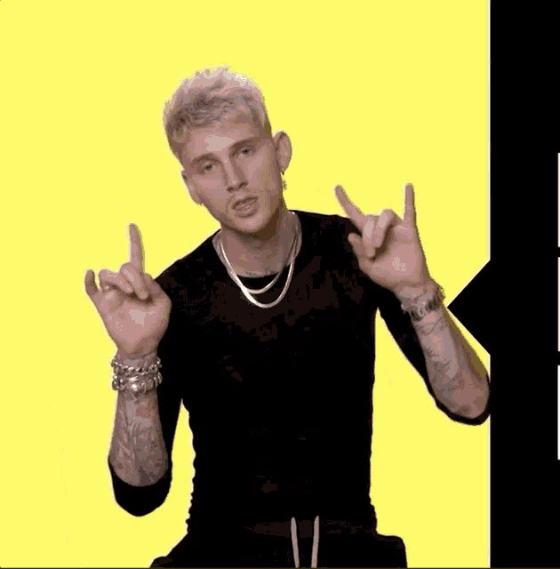 a man wearing a black shirt and a silver necklace is pointing at something