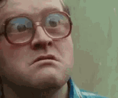 a man wearing glasses and a plaid shirt is making a face .