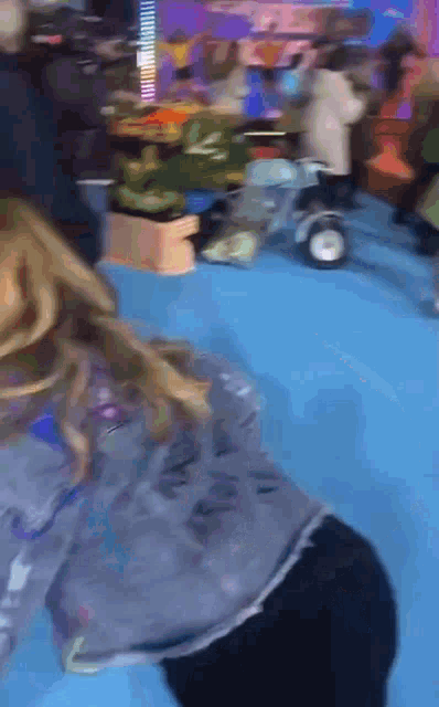 a blurry picture of a girl playing with a toy car on a blue floor