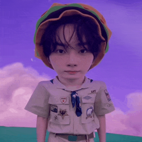 a boy in a boy scout uniform has a hamburger hat on
