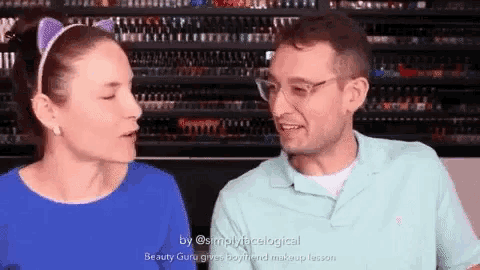 a man and a woman are talking to each other in front of a shelf filled with makeup .
