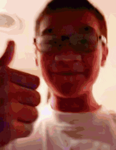 a man wearing glasses is giving a thumbs up