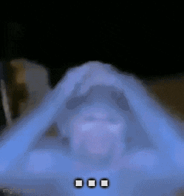 a blurry picture of a person covering their face with their hands in a dark room .