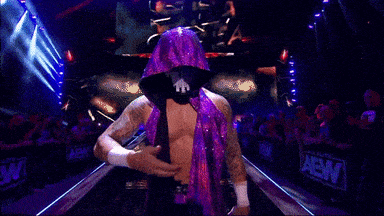 a man with a mohawk and a bandage on his head is standing in a dark room with a sign that says aew