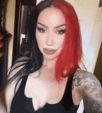 a woman with red and black hair is taking a selfie .