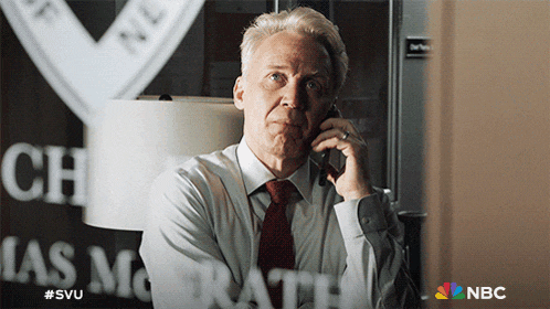a man in a suit and tie is talking on a cell phone in front of a window that says chas