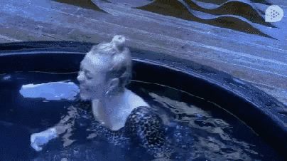 a woman in a black dress is swimming in a pool of water .
