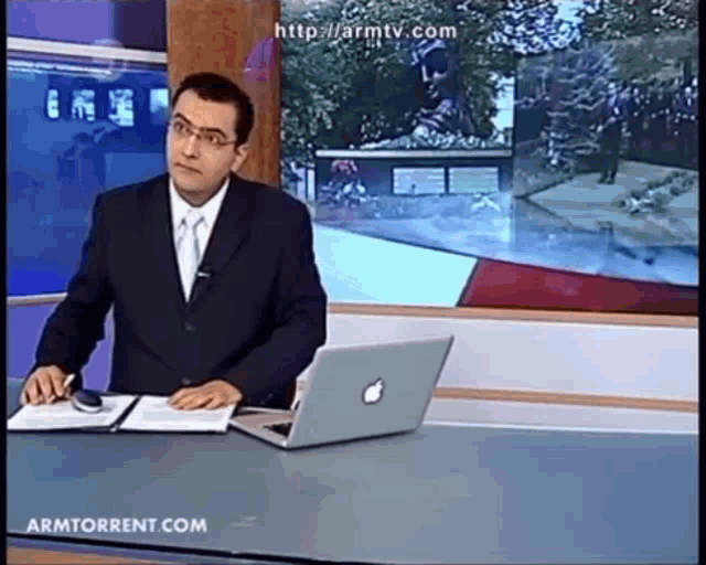 a man sitting at a desk with an apple laptop on it
